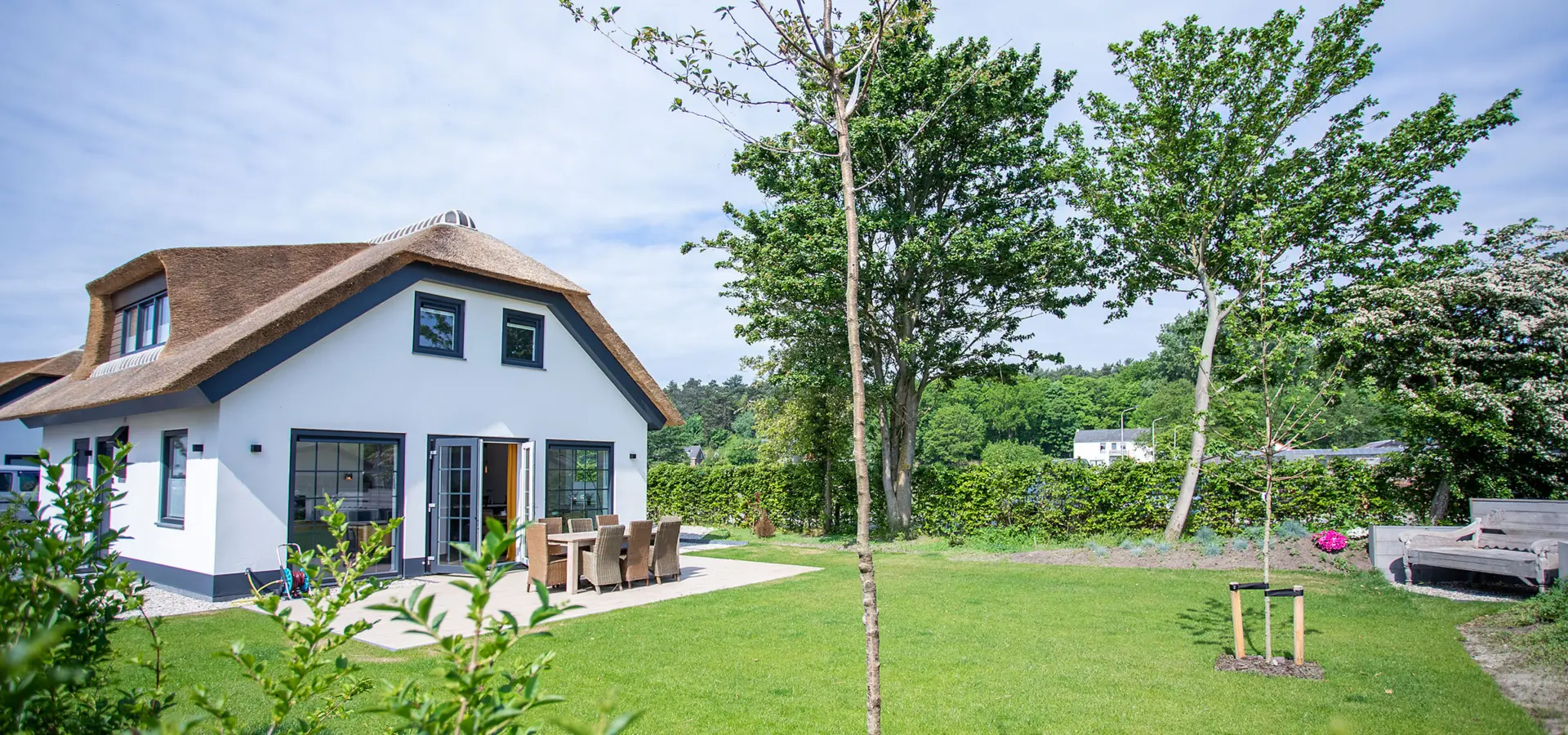 ruime tuin met terras van rietgedekte woning